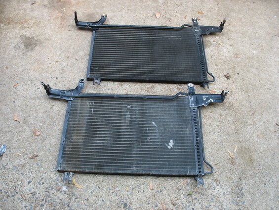 Two car radiators laid out on concrete. One is above the other