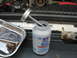 1995 Ford C-350 (Centurion Conversions) - A bottle of anti-seize lubricant sits next to a tray of bolts in an engine bay.