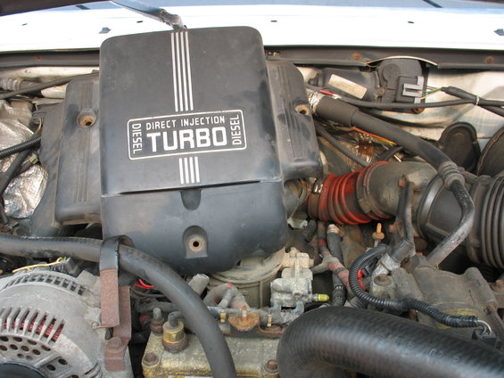 Engine bay with "DIRECT INJECTION TURBO DIESEL" cover. Visible components include alternator and hoses