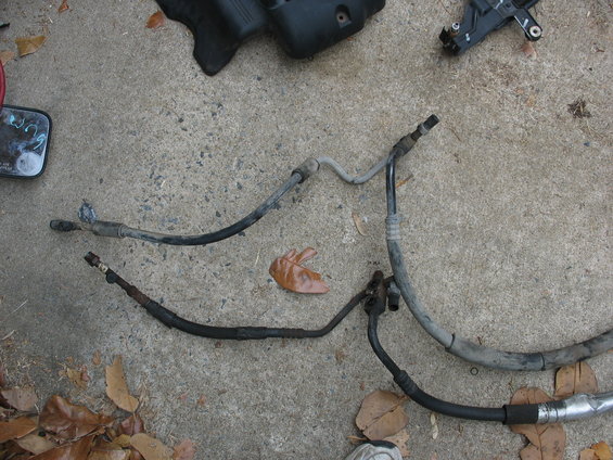 Several AC hoses laid out on concrete. Some black, some gray. One has a leaf on it