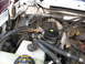 1995 Ford C-350 (Centurion Conversions) - Close-up of engine bay components, including AC system parts and coolant reservoir.