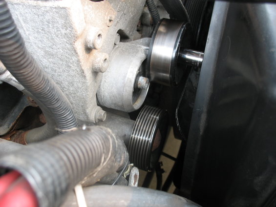 Close-up of an engine belt tensioner pulley and ribbed belt