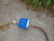 1995 Ford C-350 (Centurion Conversions) - A blue air vacuum pump is connected to hoses on a concrete surface with scattered leaves and grass.