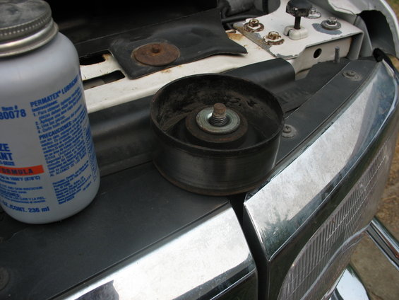 Idler pulley and Permatex lubricant bottle on vehicle's engine bay