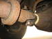 1995 Ford C-350 (Centurion Conversions) - Close-up view of the driveshaft and differential assembly on a heavily rusted vehicle.