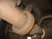 1995 Ford C-350 (Centurion Conversions) - Close-up view of rusted driveshaft and exhaust system components underneath a vehicle.