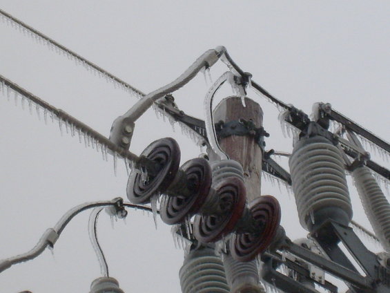 Power lines and insulators coated in ice with icicles hanging down