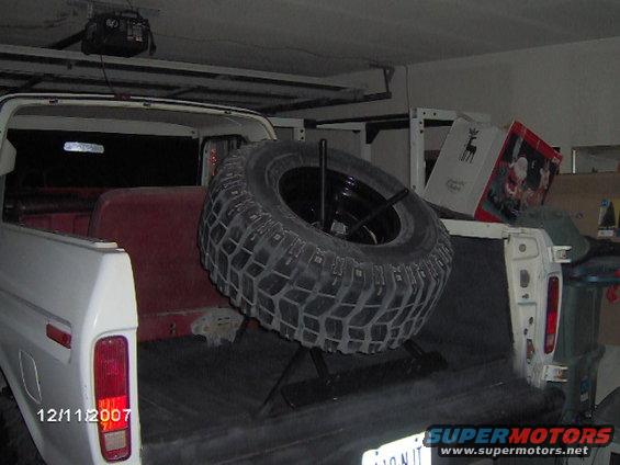 Rear of a white 1978 Ford Bronco with a spare tire mounted inside the bed. Red seats visible