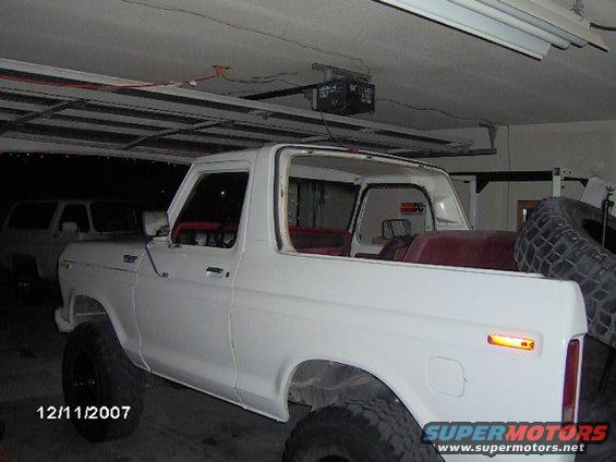 White SUV in garage, another SUV behind it. Has red interior and large tires