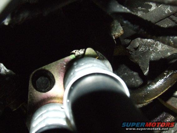 Close-up of an oil cooler line connection with a bolt and some greasy hoses