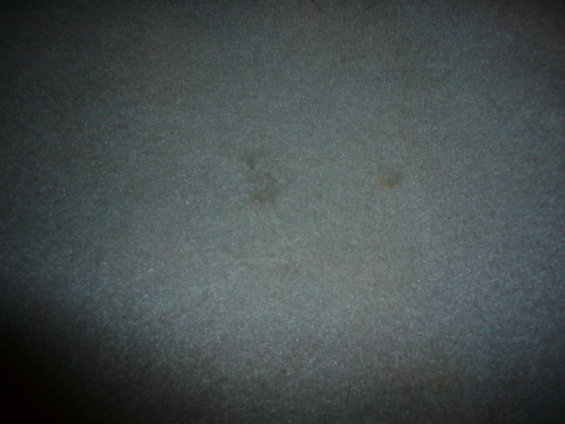 Dark, textured surface with faint smudges and discoloration