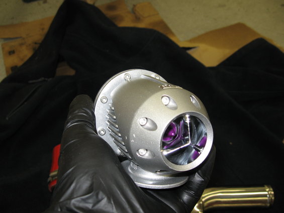 Silver blow-off valve with purple internals held in a gloved hand