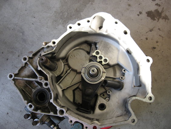 Transmission bell housing with internal components visible, resting on a concrete surface