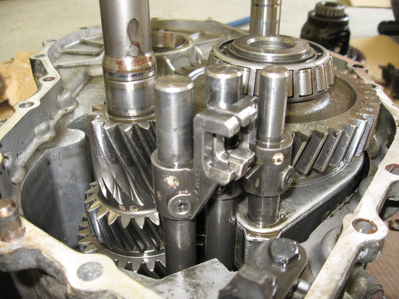 Transmission gears and shafts inside a metal casing, showing wear and oil
