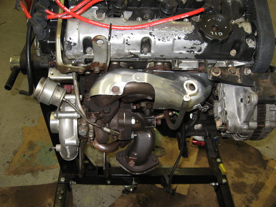 Engine assembly with turbocharger and exhaust manifold. Oil cap visible