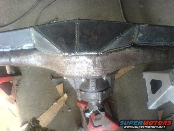 Rear axle assembly with welded metal reinforcement plates, supported by jack stands