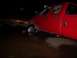 1991 Ford Bronco - A red pickup truck is partially submerged in water at night, with its front wheel deep in the murky liquid.