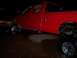 1991 Ford Bronco - A red pickup truck is shown from the side at night, with its lifted suspension and chrome wheels visible.