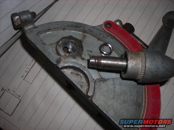 Close-up of a metal shop tool part with a threaded bolt and red measurement markings