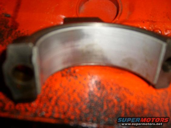 Close-up of a metal engine bearing against an orange surface