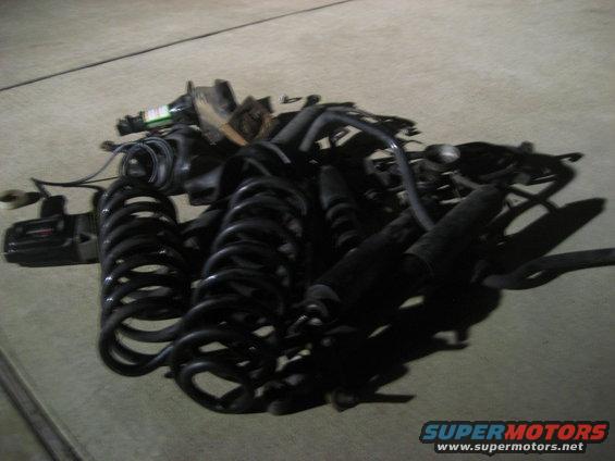 Pile of black coil springs and shock absorbers on concrete