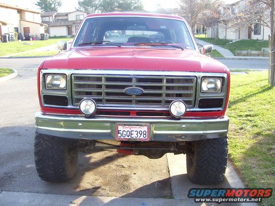 Front view of a red Ford Bronco with a chrome grille and aftermarket lights. California license plate 5GOE398 is visible