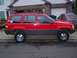 1994 Jeep Grand Cherokee - A red 1994 Jeep Grand Cherokee is parked in a driveway, showing its side profile with aftermarket wheels.