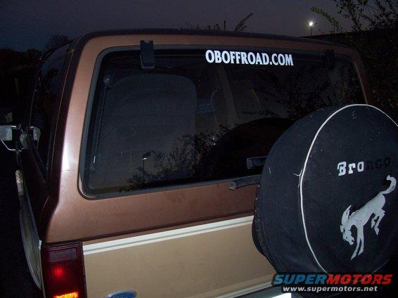 Rear view of a brown 1984 Ford Bronco II with a spare tire cover that says "Bronco" and a sticker on the window that says "OBOFFROAD.COM"