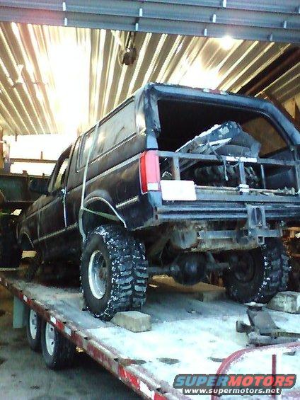 Black 1992 Ford Bronco rear view on a trailer with snow on tires