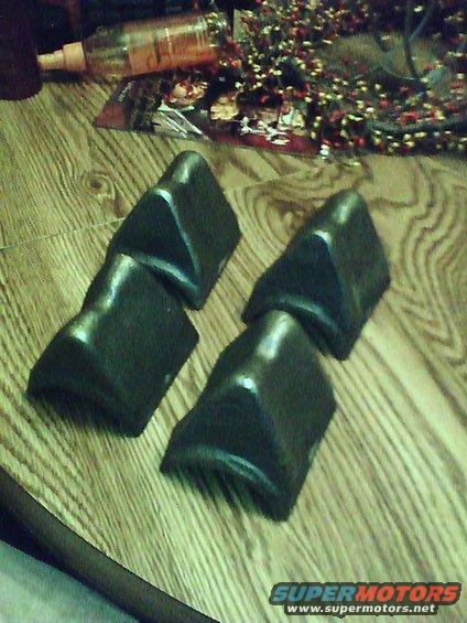 Four black plastic bumper guards on a wooden surface