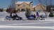 1979 Ford Bronco - Two snowmobiles are parked in a snowy yard with riders on them.