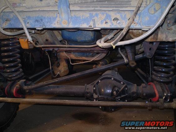 Undercarriage of a vehicle with a differential, suspension springs, and brake lines visible. Blue painted frame above