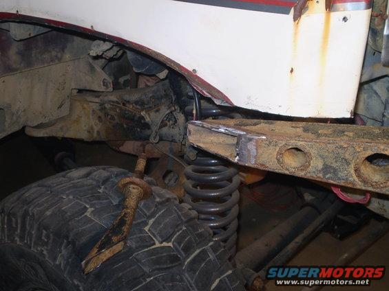Close-up of vehicle frame, suspension, and tire with rusty metal parts