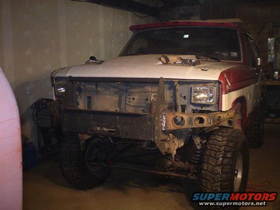 White and red Ford Bronco with a custom front bumper and large tires, front view