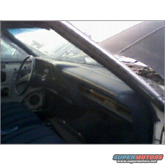 Car interior with dark dashboard, steering wheel, and blue seats. Roll bar visible