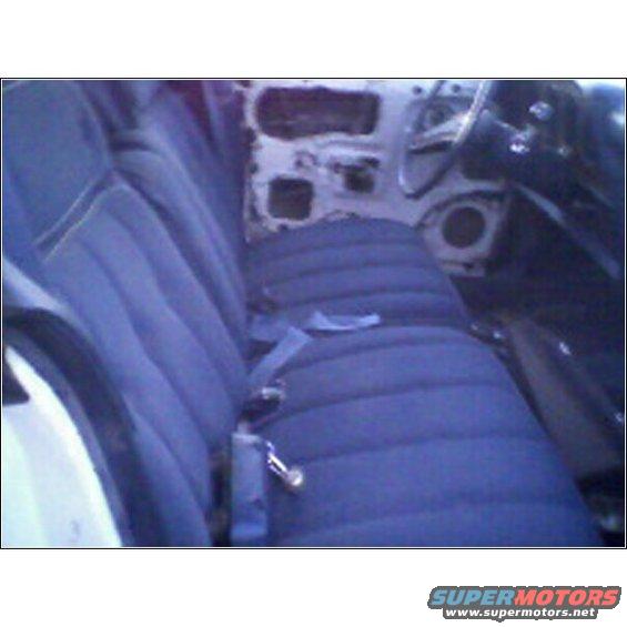 Interior view of a car with blue bench seat and seatbelts, showing door panel removed and dashboard