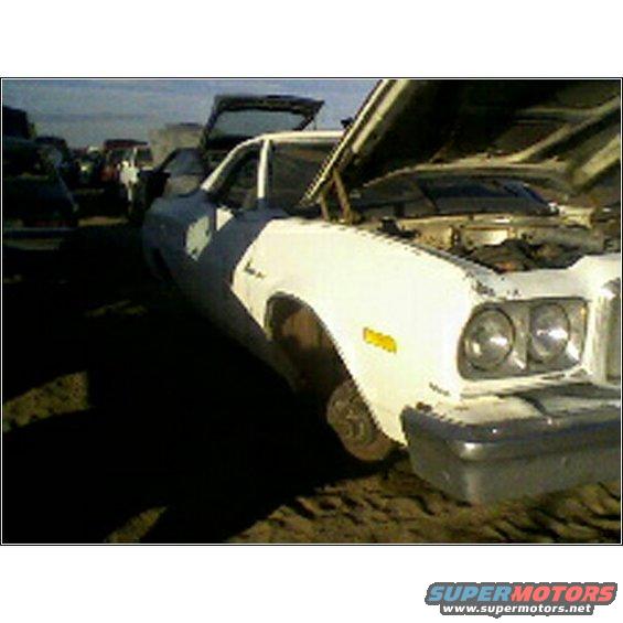 White pickup truck with hood open, parked in a junkyard with other vehicles