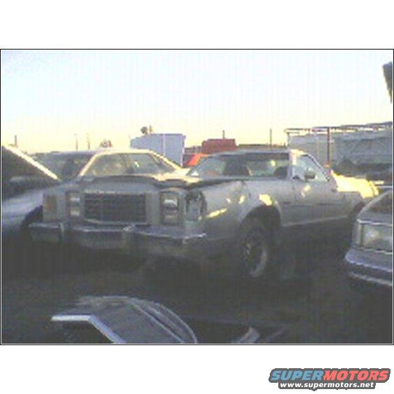 Junkyard pickup truck with damaged front end, parked next to other vehicles