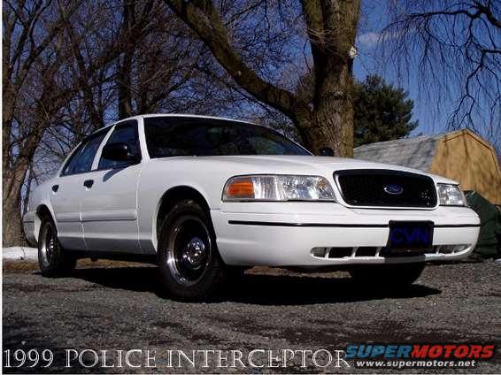 White 1999 Ford Crown Victoria Police Interceptor parked outside with trees and a shed in the background