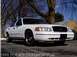 1999 Ford Crown Victoria - This white 1999 Ford Crown Victoria Police Interceptor is shown from the front three-quarter view.