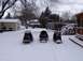1999 Ford Crown Victoria - Three snowmobiles are parked in a snow-covered yard with houses and trees in the background.