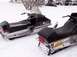1999 Ford Crown Victoria - Two snowmobiles sit in a snowy outdoor setting, with a trailer visible in the background.