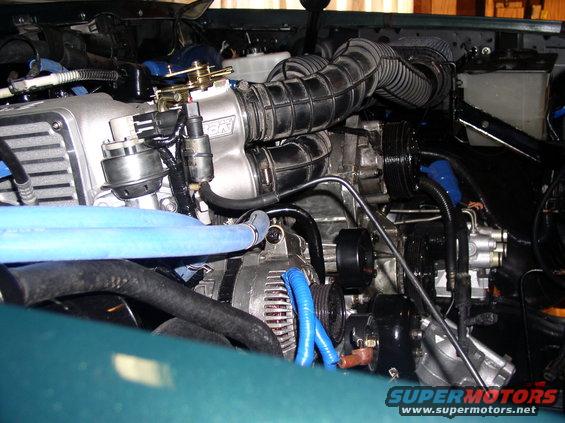 Engine bay with aftermarket intake and blue hoses. Supermotors.net logo visible