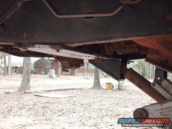 Underside of a 1990 Ford F-150 showing a straight axle swap modification with custom brackets and a shock absorber