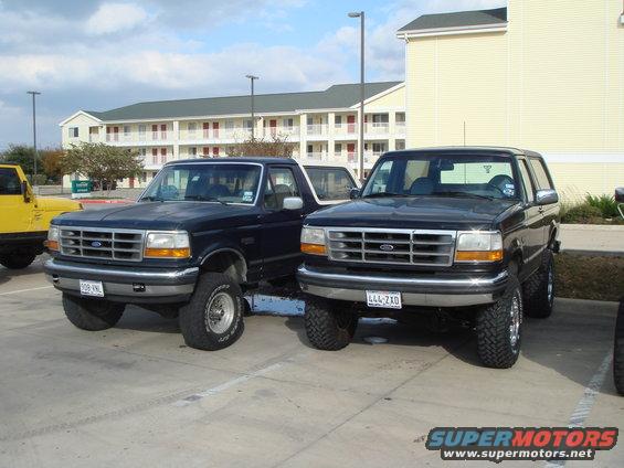 Two black Ford Broncos parked in a lot. The one on the right is a 1992 model