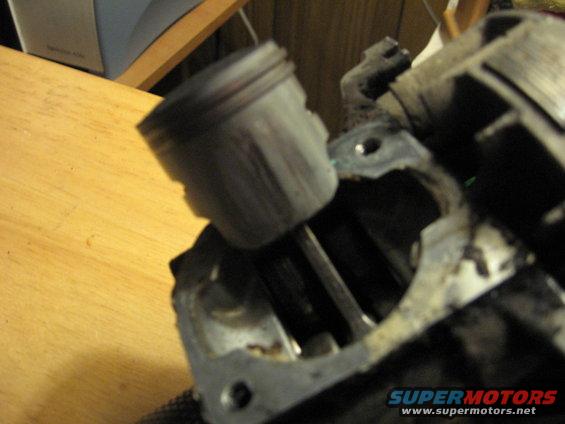 Close-up of an engine piston inside a cylinder. Part of a larger engine assembly is visible