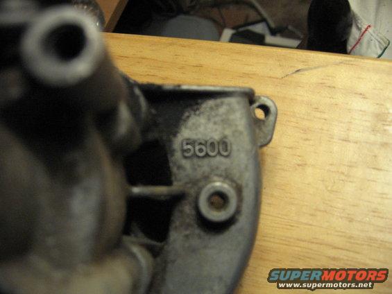 Metal part with stamped numbers 5600, on a wooden surface