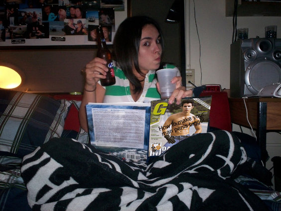 Woman holding beer and cup, magazine titled 'How to make your man penis bigger' on lap