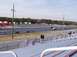 1999 Ford Crown Victoria - A drag strip scene with multiple vehicles and spectators under an overcast sky.