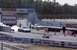 1999 Ford Crown Victoria - A white sedan performs a burnout at a drag strip, with a sports car in the foreground.